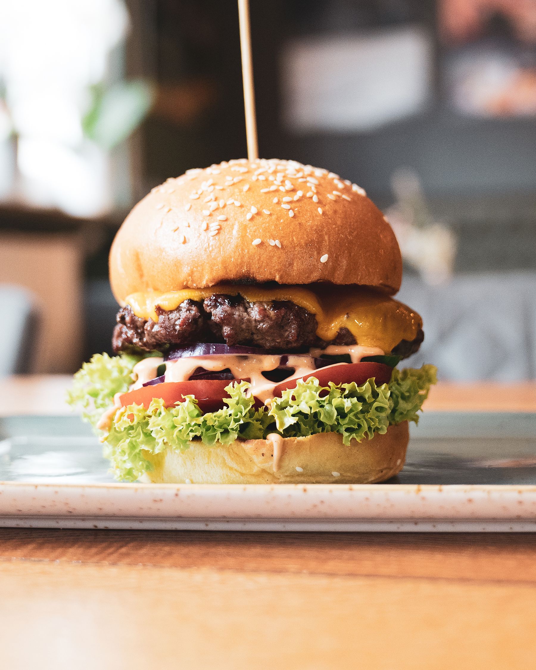 Cheeseburger mit geschmolzenem Cheddar, Salat und Tomate auf Sesambun